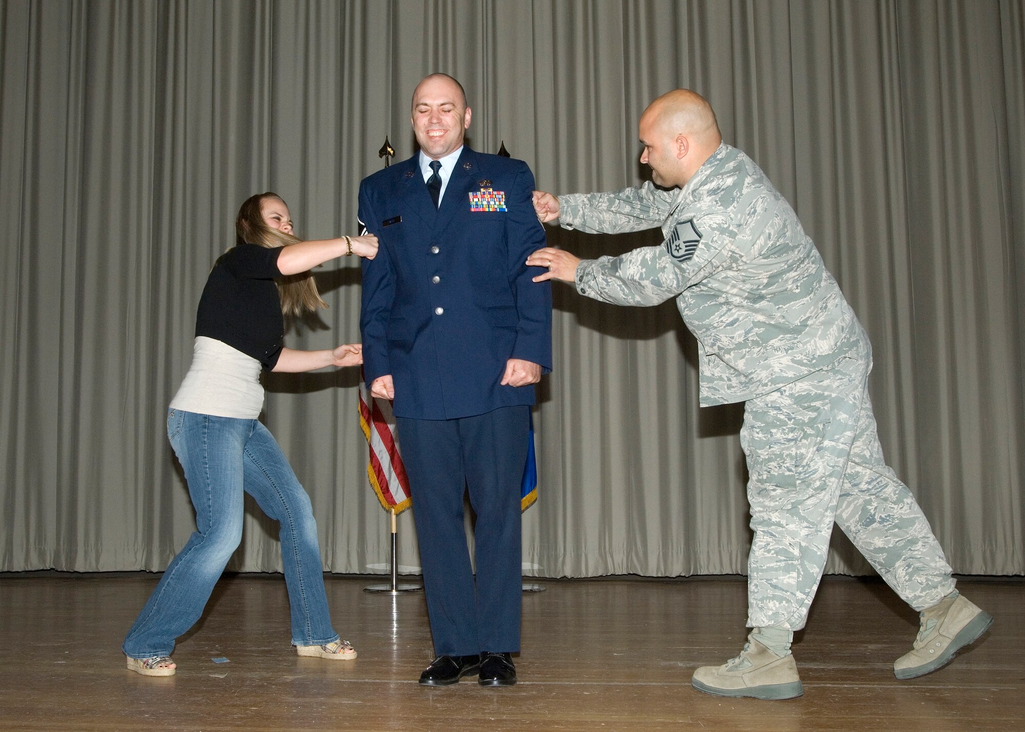 Promoted to master sergeant, Tech. Sgt. Jesse Waite, 412th Logistics Test Squadron, braces himself as his fiancé and his supervisor Master Sgt. Mark Turley, 412th MXAL, help attach the new rank. Eighteen airmen were given new ranks in the Team Edwards monthly promotion ceremony in the Base Theater, Mar. 4. (Air Force photo by Edward Cannon)