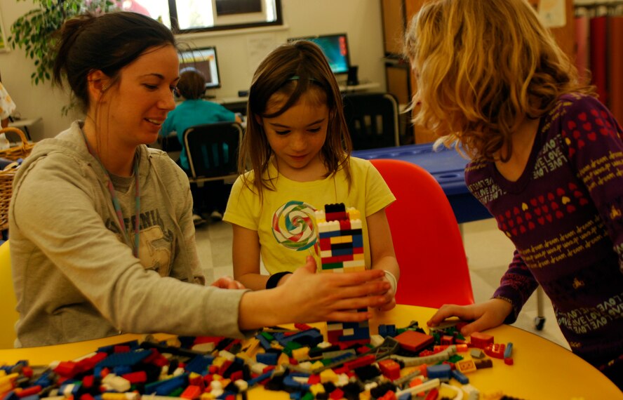 Michel Miklja builds a tower March 4, 2011 with two girls at the youth center, Ava (right) and Amber. Mrs. Miklja is the wife of a boom operator and has worked at the youth center for five months. Her favorite part of the job is working with children. “Kids are very entertaining and are just hilarious,” she said. “I laugh at things they say every day. It really is true – kids do say the darndest things.” (U.S. Air Force photo/Staff Sgt. J.G. Buzanowski)