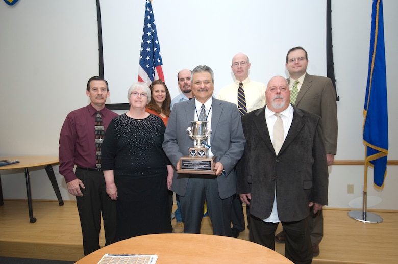 Edwards Civil Engineering Energy team members, (front row from left Dave Harrell, Amy Frost, Enrique Torres and Jack Frazier; Back row from left Minta Huddleston, Ron Ryan, James Judkins and Gerald Boetsch) pose for a picture with their new piece of hardware. The team received the Air Force Energy Conservation Award for its work in making the base more energy efficient and saving millions of dollars in the process. (Air Force photo by Rob Densmore)