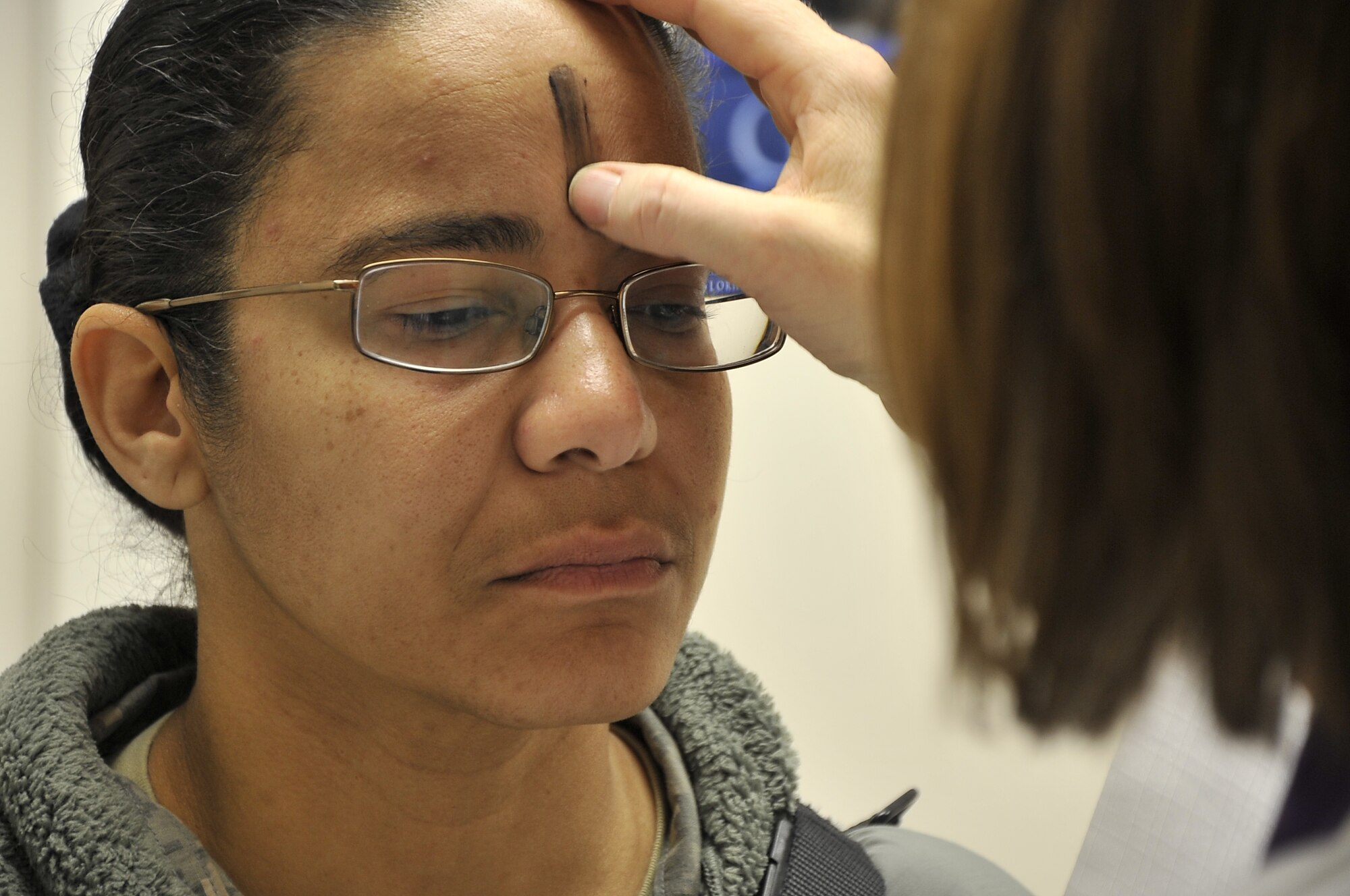 During an Ash Wednesday service, Chaplain (Maj.) Sarah Shirley imposes the mark of the cross in ash on the forehead of a soldier deployed to Bagram Airfield, Afghanistan, 9 March 2011.  Assigned to the 455th Air Expeditionary Wing, Chaplain Shirley provides spiritual guidance at the Craig Joint Theater Hospital. (U.S. Air Force photo by Staff Sgt. Larry Moore)
