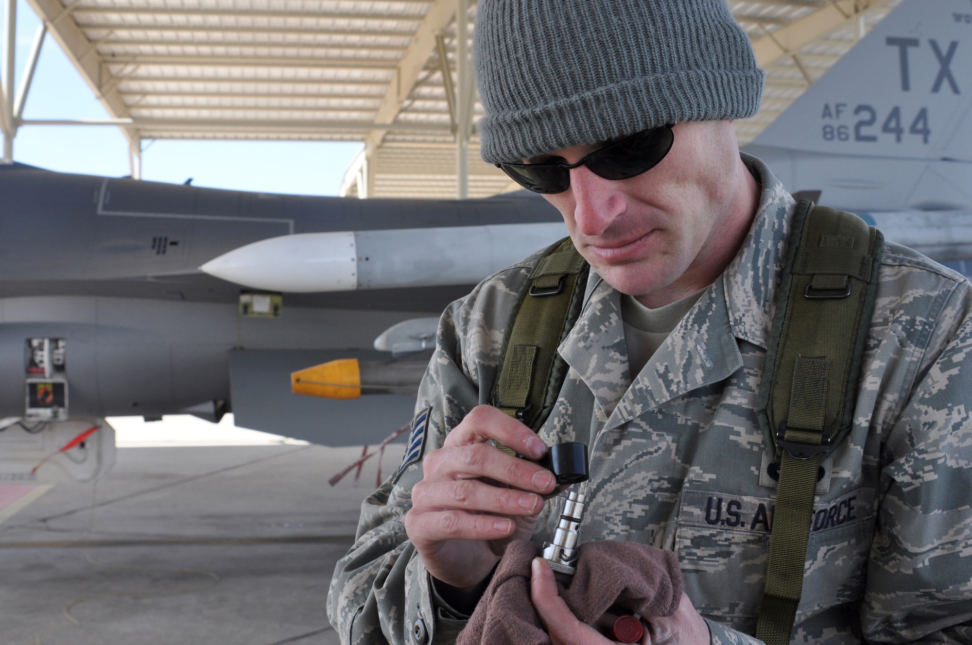 Staff Sgt. Taylor Myers checks a magnet for metal fragments during a "thru-flight" inspection on an F-16C at  Naval Air Station Fort Worth Joint Reserve Base, Texas, March 5.  The magnet is removed from the bottom portion of the plane's engine and is designed to attract metal fragments, which would be an indication of excessive wear and tear on the aircraft's power plant.  Sergeant Myers is a crew chief in the 301st Aircraft Maintenance Squadron and was supporting a "surge" exercise to help prepare the Air Force Reserve's 301st Fighter Wing for an upcoming inspection.   The 301st Maintenance Group generated 38 sorties in one day, which were flown by pilots from the wing's 457th Fighter Squadron.  (U.S. Air Force photo/Lt. Col. David Kurle)