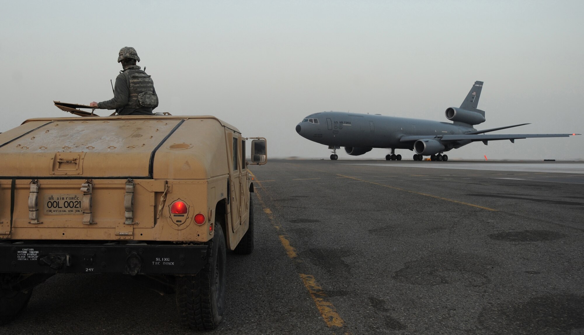Airman 1st Class Caitlin Chamberlain, 380th Expeditionary Security Forces Squadron, looks on as a KC-10 Extender that she helps protect on a daily basis, taxies past Feb. 18, 2011, in Southwest Asia. Security Forces are on 24-hour watch at every post, keeping the installation secure. Airman Chamberlain is deployed from the 75th SFS, Hill AFB, Utah. (U.S. Air Force photo by Senior Airman Maynelinne De La Cruz)