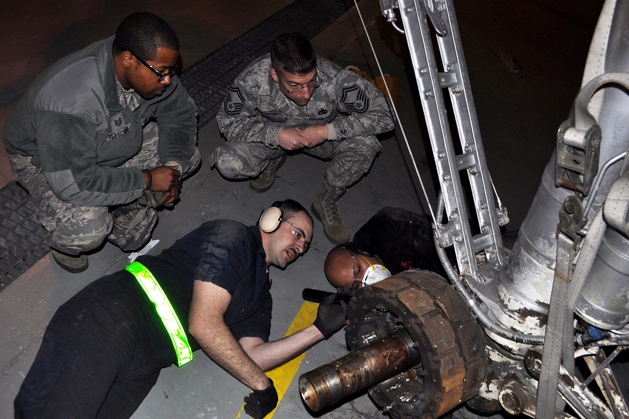 JOINT BASE MCGUIRE-DIX-LAKEHURST, N.J. -- Airmen from the 514th Maintenance Group and 305th Maintenance Squadron evaluate the progress of the removal of a mount that was connected to the landing gear of a C-118 Liftmaster in an aircraft maintenance hangar here March 4, 2011. Liftmasters were the first cargo airplanes stationed here and helped the base to define its role as an air mobility gateway. The C-118 is being restored by active-duty Airmen, Reserve Airmen and civilians in an effort to return the aircraft to its position as a static display on the traffic circle near the passenger terminal here. Pictured here are: Technical Sergeants Justin Fletcher (top left), 514th MXG; Joseph Martinek (bottom left), 305 MXS; Jarod Jones (bottom right), 305th MXS; and Senior Master Sgt. Christopher Hofrichter, 514th MXG. (U.S. Air Force photo/Tech. Sgt. Shawn J. Jones)