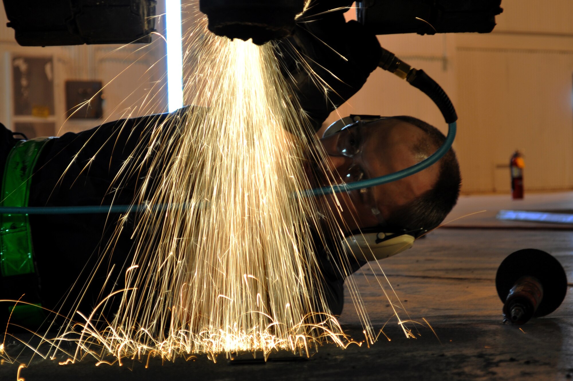 JOINT BASE MCGUIRE-DIX-LAKEHURST, N.J. ? Sparks bounce off the floor as Tech. Sgt. Joseph Martinek, a metals technology specialist with the 305th Maintenance Squadron, grinds down a mount that was connected to the landing gear of a C-118 Liftmaster in an aircraft maintenance hangar here March 4, 2011. Liftmasters were the first cargo airplanes stationed here and helped the base to define its role as an air mobility gateway. The C-118 is being restored by active-duty Airmen, Reserve Airmen and civilians in an effort to return the aircraft to its position as a static display on the traffic circle near the passenger terminal here. (U.S. Air Force photo/Tech. Sgt. Shawn J. Jones)