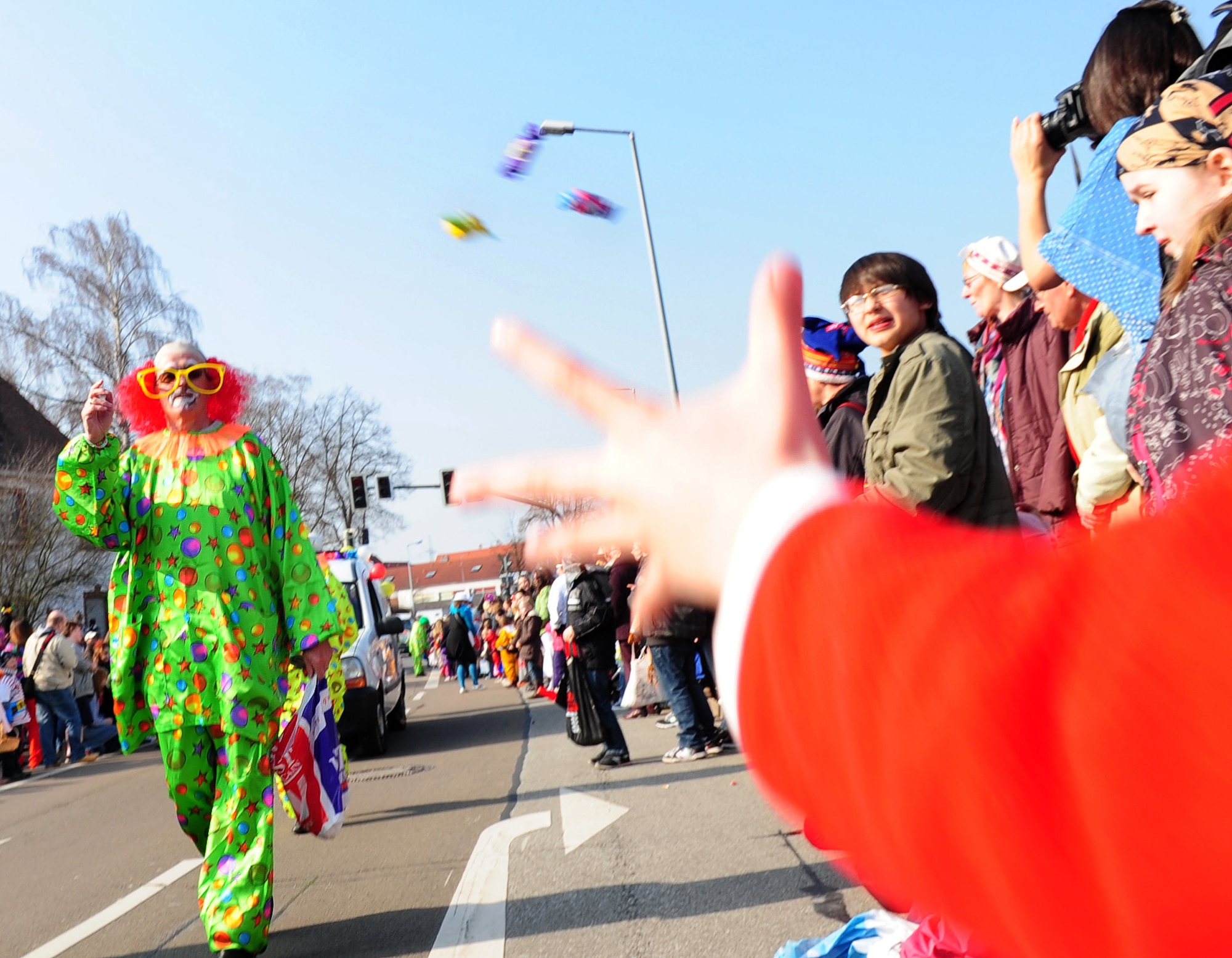 A parade participant dressed as a clown throws candy into the crowd during the annual celebration of Fasching parade, Ramstein village, Germany, March 8, 2011. This annual event is a pre-Lenten carnival which is celebrated with the donning of wild and fancy costumes to chase away the evil spirits of winter in preparation for spring.(U.S. Air Force photo by Senior Airman Brittany Perry)