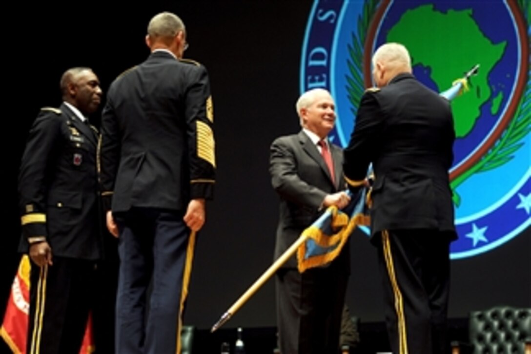 Secretary of Defense Robert M. Gates passes the colors to incoming commander of U.S. Africa Command Army Gen. Carter Ham signifying the assumption of command by Ham while outgoing commander Army Gen. William Ward (left) looks on during the AFRICOM change of command ceremony at Sindelfingen Stadthalle City Hall in Stuttgart, Germany, on March 9, 2011.  
