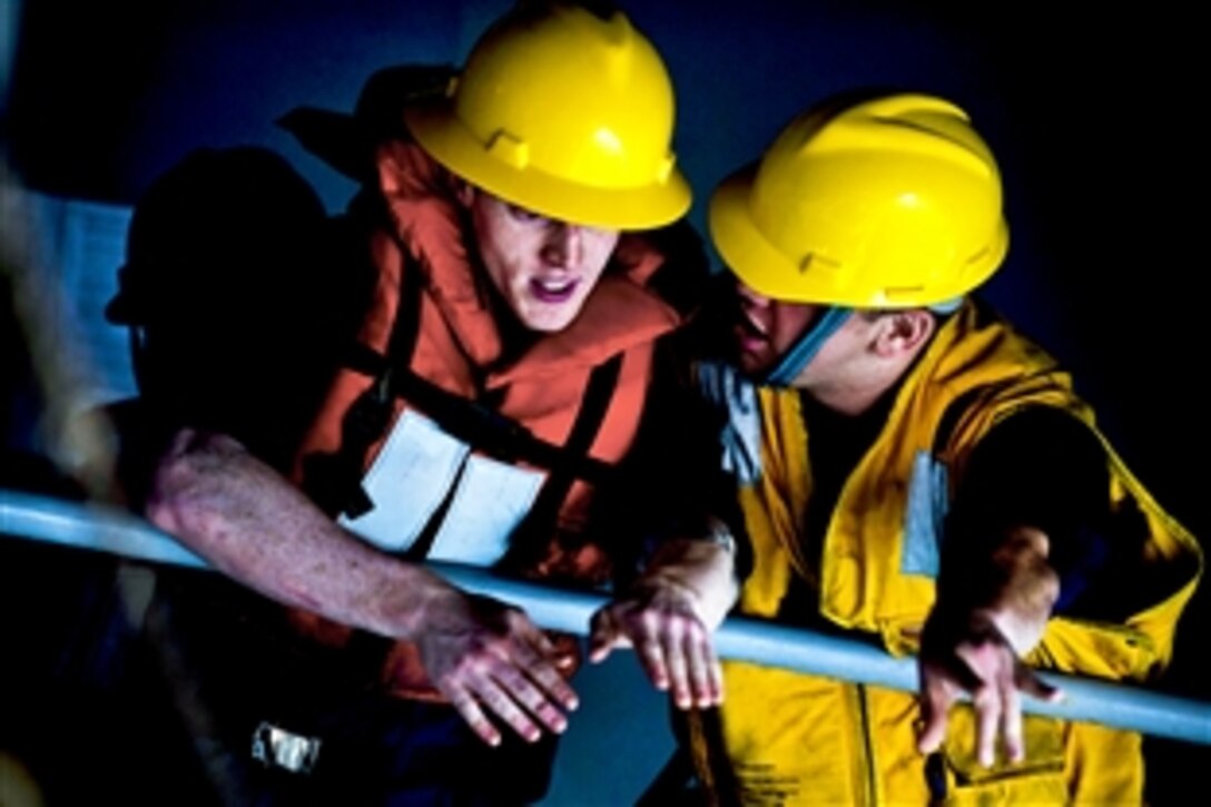 U.S. Navy Petty Officer 3rd Class Christopher Cook instructs Petty Officer 3rd Class Kevin Doty inside the rigid-hull inflatable boat during a man overboard drill aboard the aircraft carrier USS Carl Vinson, which is underway in the Arabian Sea, March 1, 2011.