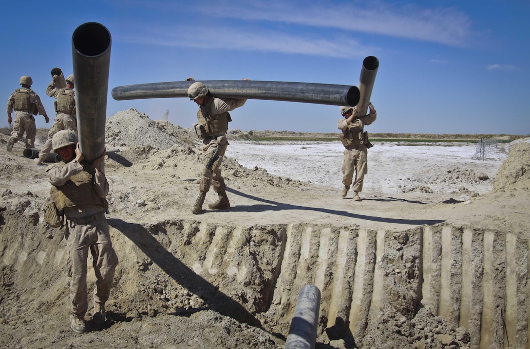 Combat engineers and heavy equipment operators with Combat Logistics Battalion 3, 2nd Marine Logistics Group (Forward), remove plastic tubing from a culvert site in Haji Hanif Khan, Afghanistan, March 10. Haji Hanif Khan is a small rural community located in Afghanistan's Helmand province.