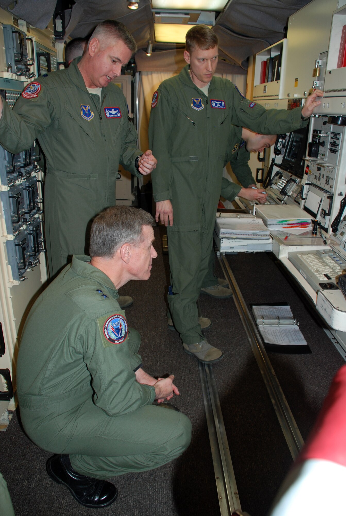 Maj. Gen. William Chambers, Assistant Chief of Staff for Strategic Deterrence and Nuclear Integration, Headquarters U.S. Air Force, kneels down for a closer look at the operator’s screen while Lt. Col. David Martinson, 319th Missile Squadron commander, explains a typical alert in the capsule with the assistance of 1st Lt. Frank Timothy, 319th MS March 8. (U.S. Air Force photo by 1st Lt. Brooke Brzozowske)

