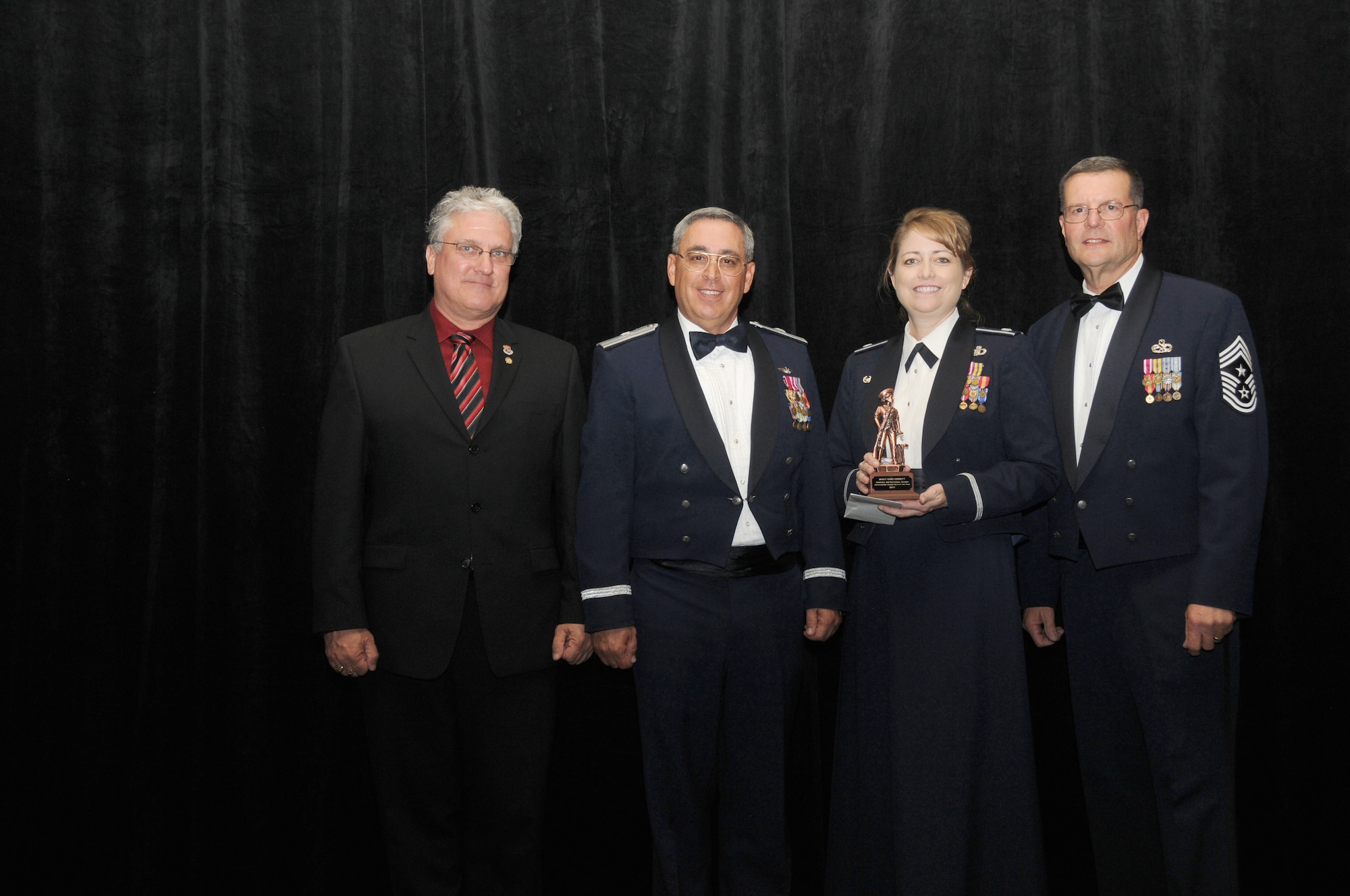 Master Sgt. Kris Errett from the 107th Air Control Squadron, Phoenix Ariz, is the Arizona Air National Guard’s Senior Noncommissioned Officer of the Year. On her behalf, Lt. Col. Lynda Lovell, Commander 107th Air Control Squadron accepts her award from Mr. Glenn Klassen, President Arizona National Guard Patriots, Brig. Gen. Michael Colangelo, Commander, Arizona Air National Guard and Chief Daniel Irving, Arizona State Command Chief on Saturday March 5, 2011.  (U.S. Air Force photo by Airman 1st Class Rashaunda Williams/Released)