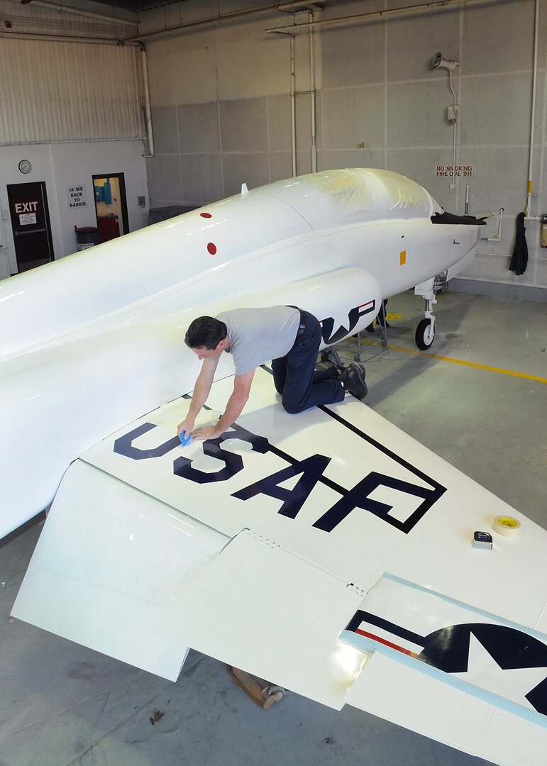 Neil Orlowski, 12th Flying Training Wing corrosion control, applies 1960s-style decals to a T-38 Talon at Randolph Air Force Base March 10. To commemorate the 50th anniversary of the aircraft March 17, the aircraft was painted in it's original paint scheme. (U.S. Air Force photo/David Terry)