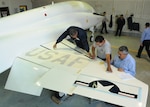 To commemorate the 50th anniversary of the T-38 Talon March 17, Danny Rodriguez, Mario Tarin and Frank Garcia, 12th Flying Training Wing corrosion control, apply 1960s-style decals to the wings of an aircraft March 10. The aircraft was painted white in the same paint scheme used on the aircraft during its early years at Randolph. (U.S. Air Force photo/David Terry)