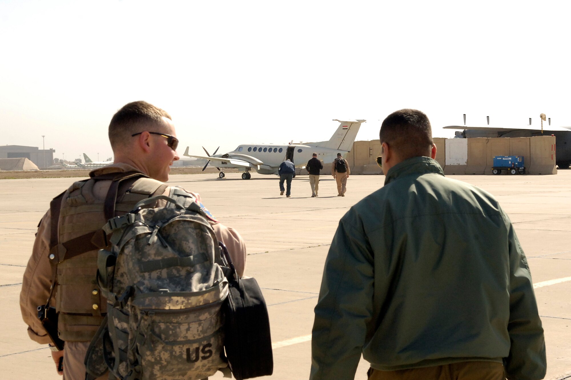 BAGHDAD -- U.S. Navy Lt. Philip Ritchie, King Air Military Training Team training officer, and an Iraqi pilot with Squadron 87 head for a King Air 350 on the flightline at New Al-Muthana Air Base March 3.  Both pilots were scheduled for a mission dedicated to enhancing the Iraqi pilot’s skills and Sq87’s overall effectiveness. Lieutenant Ritchie, an Austin, Texas, native, is deployed from Naval Air Station Corpus Christi, Texas. (U.S. Air Force photo by Tech. Sgt. Randy Redman)