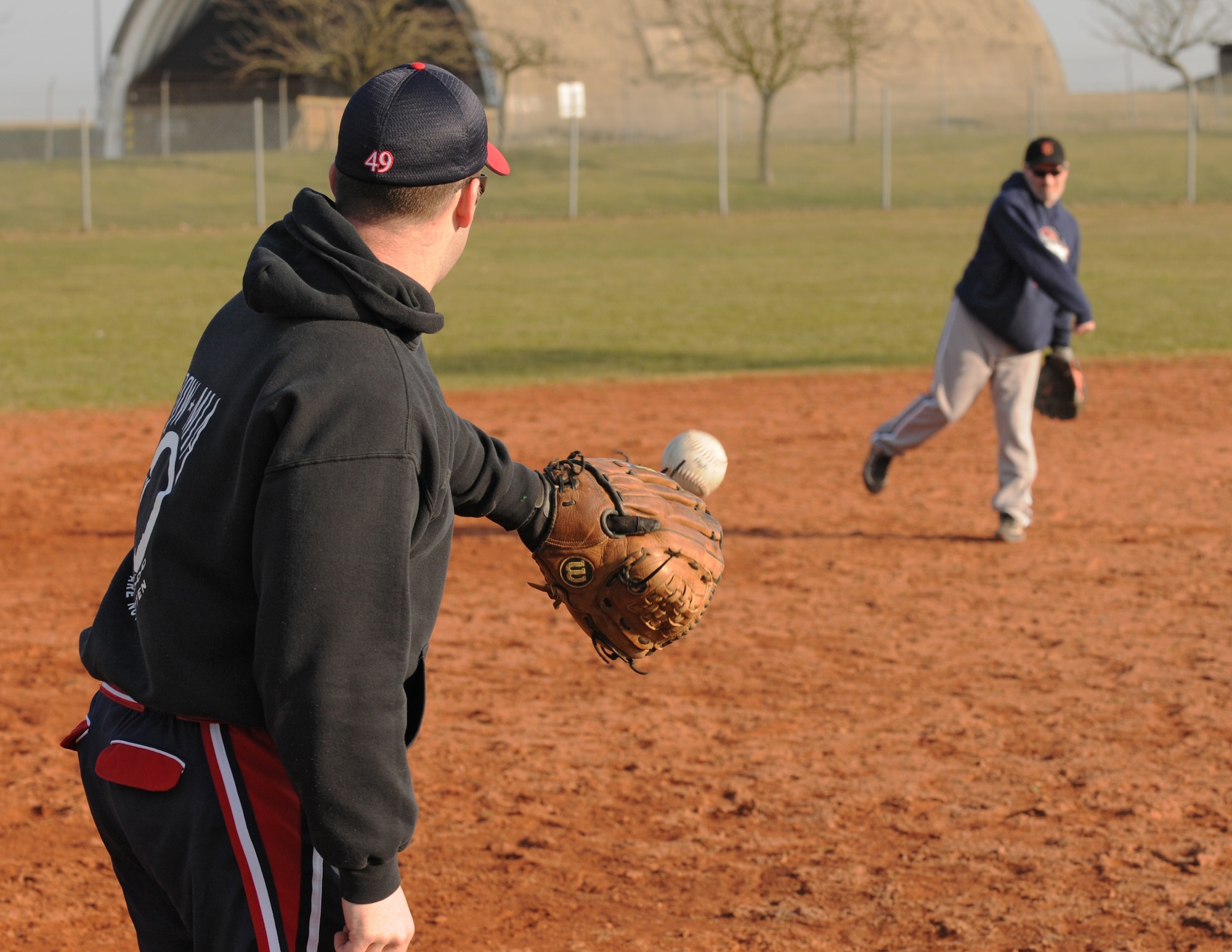 SPANGDAHLEM AIR BASE, Germany –Daniel Wiggins, 52nd Operations Support Squadron, catches a softball thrown by John Downey, 52nd Mission Support Group, while they wait for batting practice to start on varsity field 1 March 8. The Spangdahlem Sabers Men’s varsity softball team is currently holding tryouts and practice until March 18. The team competes in tournaments throughout Europe, playing against other Air Force, Army, and Navy teams.  (U.S. Air Force photo/Airman 1st Class Matthew B. Fredericks)