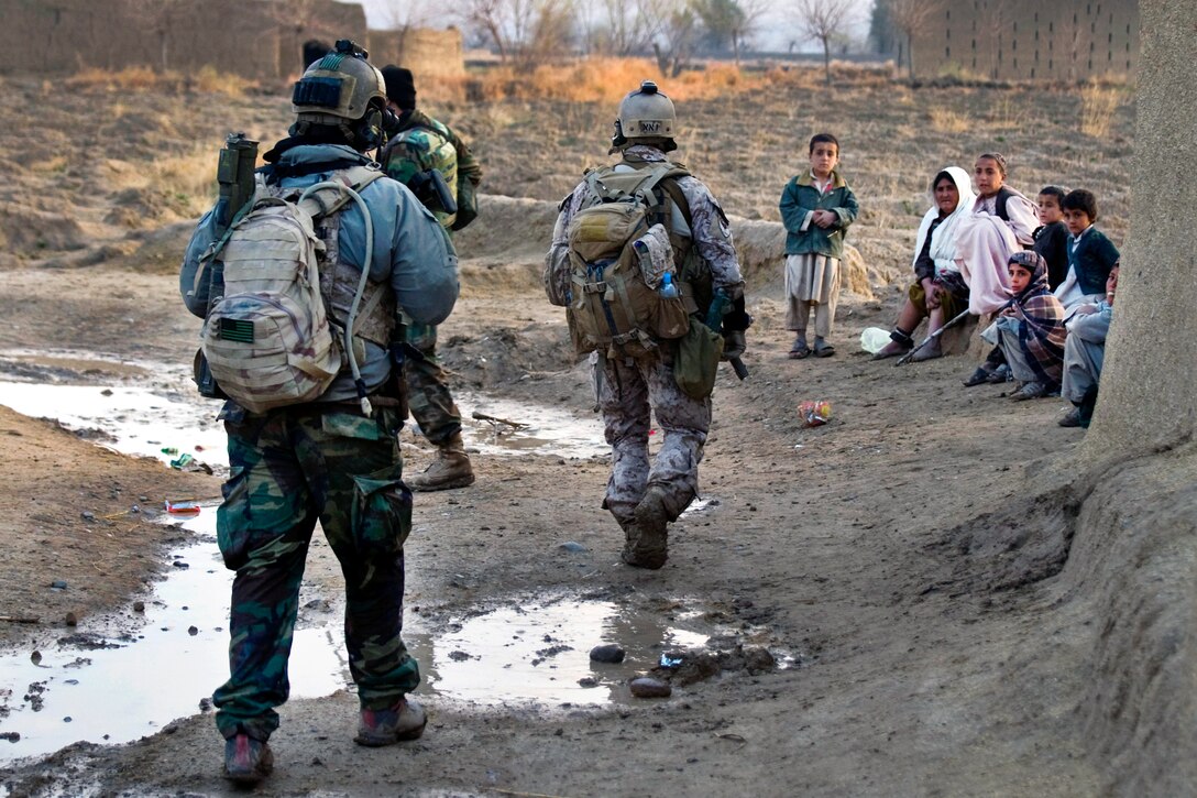 U.S. Special Forces soldiers and Afghan commandos pass a group of Afghan women and children in the Zharay district, Kandahar province, Afghanistan, March 6, 2011.