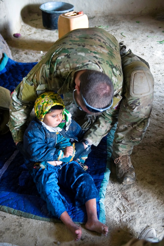 A U.S. Air Force pararescue jumper performs a medical assessment on a young girl in the Zharay district, Kandahar province, Afghanistan, March 6, 2011. The pararescue jumper is assigned to Special Operations Task Force South. The girl's father brought her to the U.S. forces for treatment.