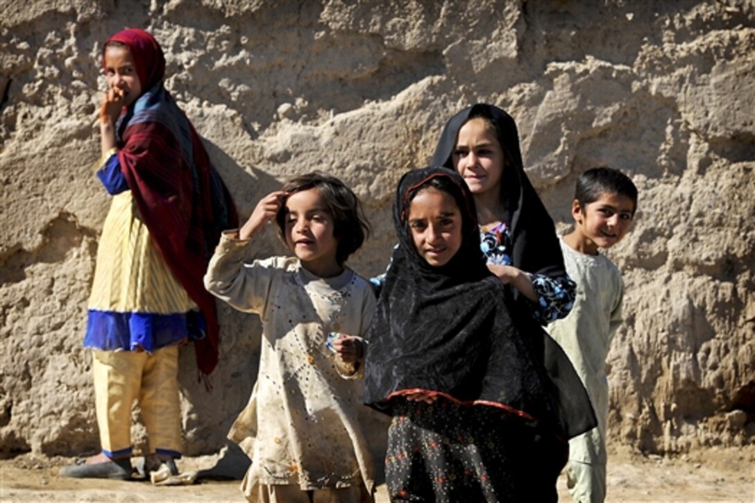 Afghan children watch as U.S. Defense Secretary Robert M. Gates tours the village of Tabin in Afghanistan, March 8, 2011.