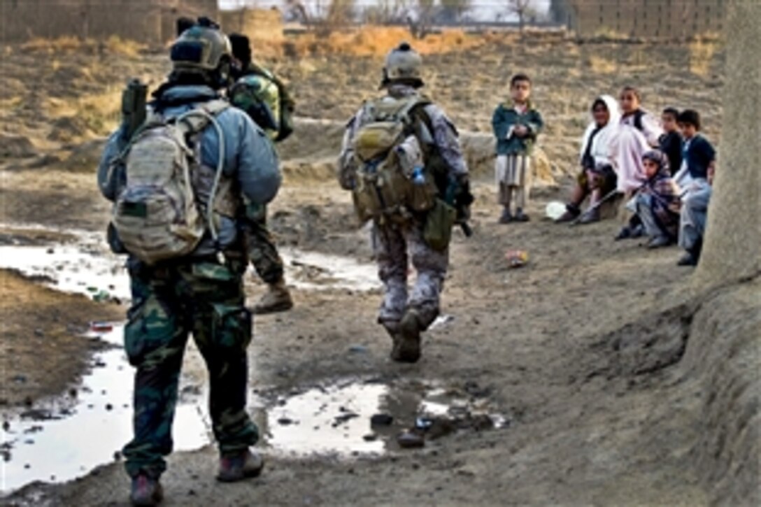 U.S. Special Forces soldiers and Afghan commandos pass a group of Afghan women and children during an operation to hinder insurgent activity in the Zharay district in Afghanistan's Kandahar province, March 6, 2011. The soldiers are assigned to Special Operations Task Force South. The Afghan-led operation yielded 200 pounds of homemade explosives.