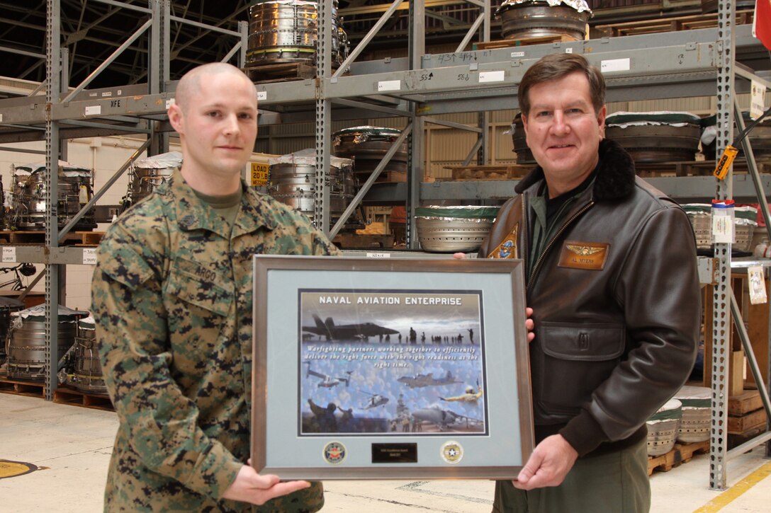 Vice Admiral Allen G. Myers, commander, Naval Air Forces, U.S. Pacific Fleet, presents the Naval Aviation Enterprise award to Staff Sgt. Olen L. Argo, a Marine Aviation Logistics Squadron 12 electronics technician, at the Power Station here March 11 for his hard work and dedication. Argo recieved the award for leading an advanced Lean Six Sigma Continuous Process Improvement Black Belt project to investigate and correct a problem with airfcraft maintenance repair impacting readiness in Marine Air Group 12.