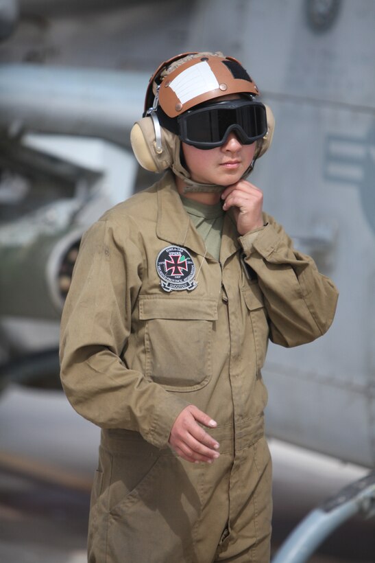 Cpl. Kelsey J. Canoy, a helicopter mechanic with Marine Light Attack Helicopter Squadron 169, tightens her protective helmet before heading to the flightline at Camp Bastion, Afghanistan, March 11. “We are responsible for the equipment on the aircraft,” said Canoy. “We make sure everything is tightened down and ready for launch.”::r::::n::::r::::n::::r::::n::