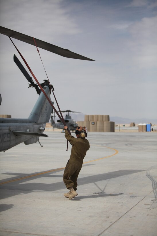 Cpl. Kelsey J. Canoy, a helicopter mechanic with Marine Light Attack Helicopter Squadron 169, removes the straps from the rotor blades of an AH-1W Cobra in preparation for the helicopter's launch from Camp Bastion, Afghanistan, March 11. “I love my job,” said Canoy. “I feel like an important part of the bigger picture.”::r::::n::::r::::n::::r::::n::