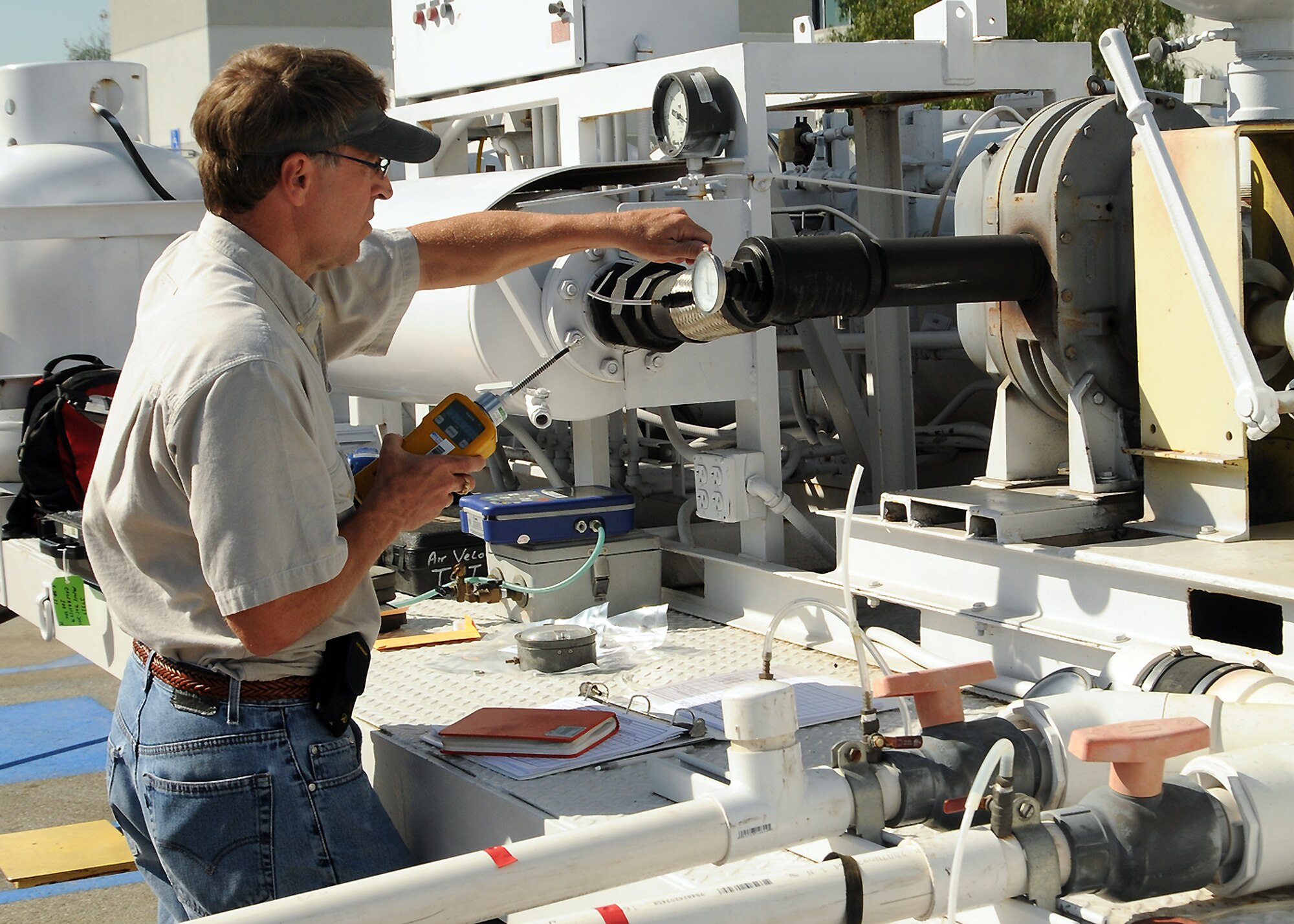 A technician checks the soil vapor extraction system located at the site of the old AAFES gas station on Los Angeles AFB, March 10. Sampling at the site found vapor phase residual petroleum constituents and methane impacting soil and groundwater. An SVE system was selected as the remediation method. A pilot test is being conducted to collect air flow, radium of influence and mass removal rate data for the design of a full-scale SVE system. (Photo by Jim Gordon)