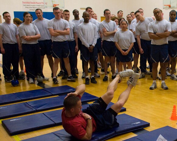 NELLIS AIR FORCE BASE, Nev.-- Staff Sgt. Tyler Meyenburg, Airman Leadership School instructor, demonstrates the proper way to execute an oblique crunch during a physical training session at the fitness center. Over the past year, Nellis ALS instructors have been developing a comprehensive, constantly-changing PT program to greatly improve the physical fitness of their students. (U.S. Air Force photo by Airman 1st Class Jamie Nicley)