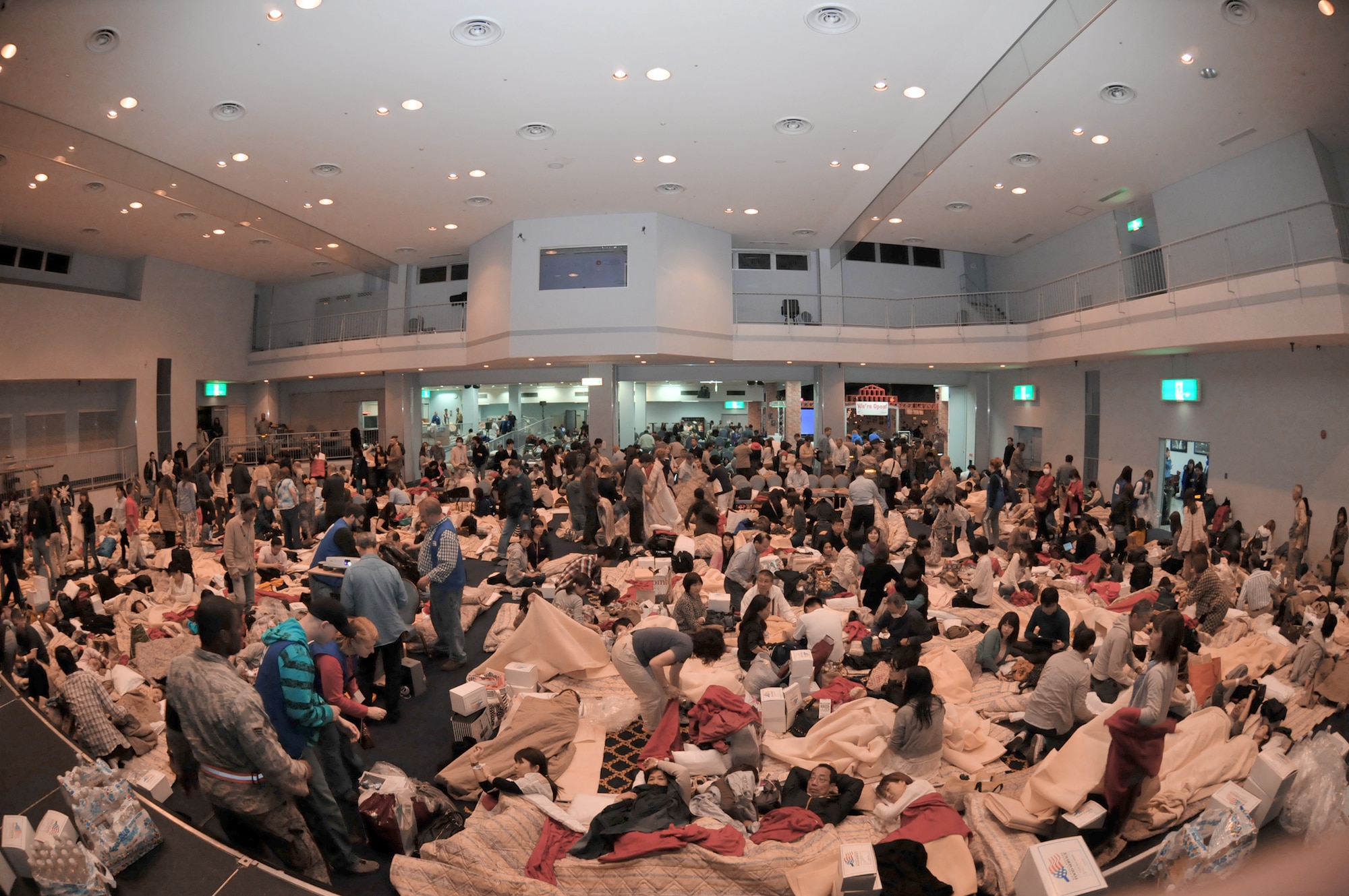 American Red Cross volunteers provide blankets and pillows to passengers of a commercial airline flight taking shelter March 11, 2011, at Yokota Air Base, Japan. The passengers arrived at the base after their flights were diverted from Narita International Airport in Tokyo, due to an 8.9-magnitude earthquake. (U.S. Air Force photo/Airman John D. Partlow)