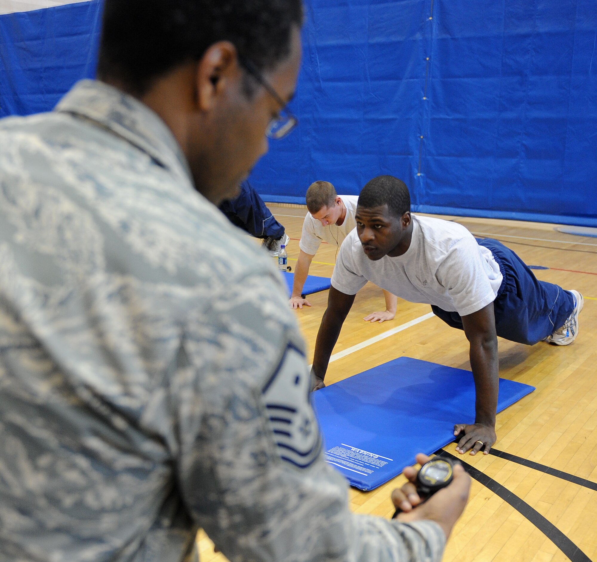 Push-up-A-Thon/Sit-up-A-Thon Participant Airman 1st Class Donald Akins, 633d Medical Group pharmacy technician focuses on his next push-up while Master Sgt. Steven Dawson, 633d Force Support Squadron first sergeant watches the clock at Langley Air Force Base, Va., March 11, 2011. The Langley First Sergeants sponsored this fitness event in order to raise funds for the Enlisted Heritage Hall. (U.S. Air Force photo by Senior Airman Antoinette Gibson/Released)