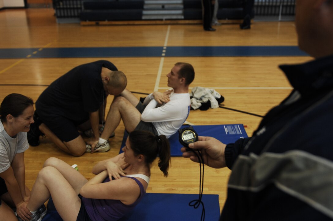 Master Sgt. Duane Smith, 15th Intelligence Squadron first sergeant, times Tech. Sgt. Therasa Carlson, Air Combat Control command and control policy and procedures, and Daniel Williams, ACC emergency mass notification system technician, during the Push-up-A-Thon/Sit-up-A-Thon at Langley Air Force Base, Va., March 11, 2011. The fitness event was sponsored by the Langley first sergeants in order to be donated to the Enlisted Heritage Hall museum. (U.S. Air Force photo by Airman 1st Class Kayla Newman/Released)