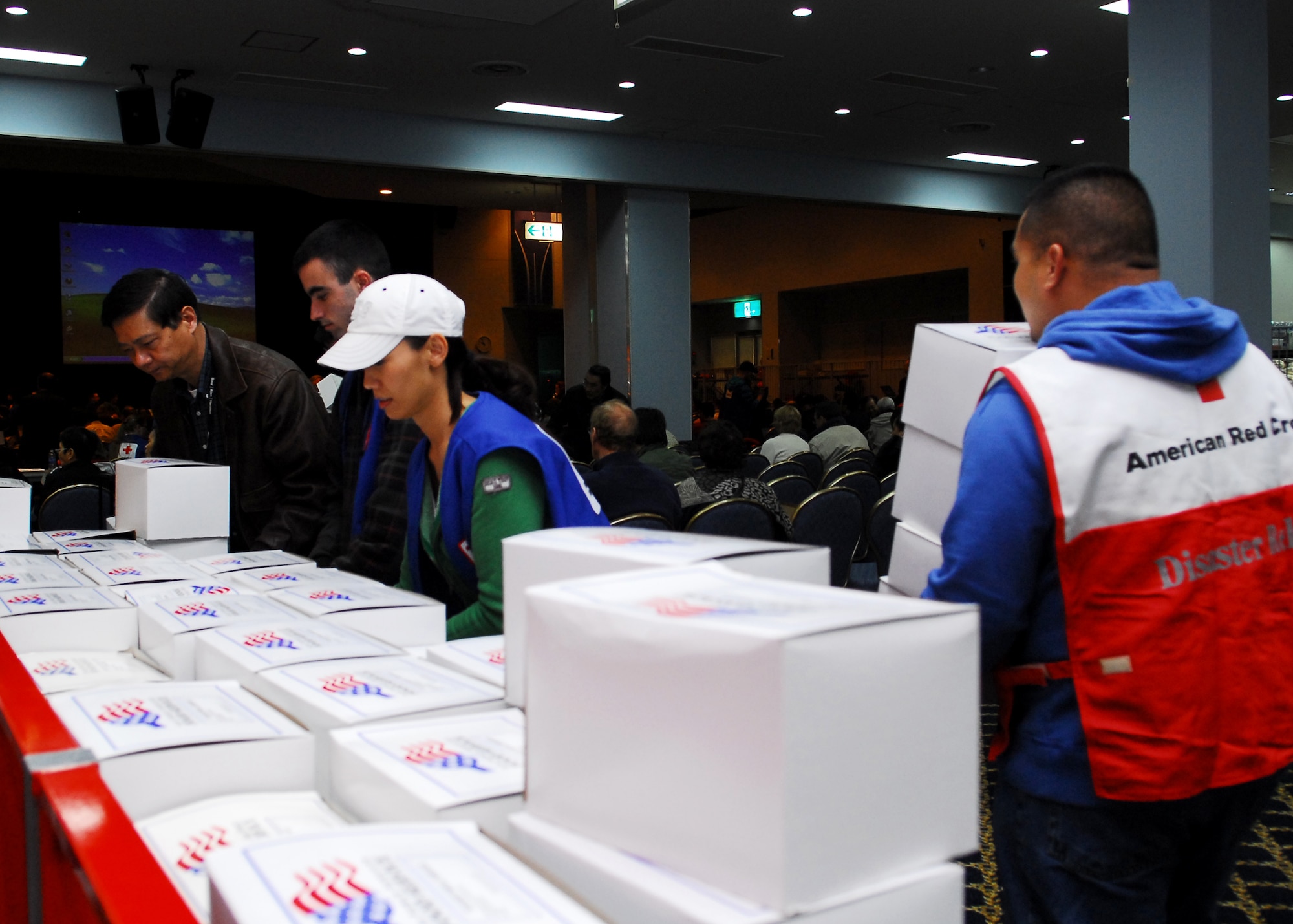 YOKOTA AIR BASE, Japan -- American Red Cross volunteers give boxed meals provided by the 374th Force Support Squadron, to passengers at the Taiyo Community Center here March 11. The passengers arrived to the base after their commercial flights were diverted from Narita International Airport, Tokyo, Japan, following an earthquake that struck near Tokyo. (U.S. Air Force photo/Airman 1st Class Andrea Salazar)