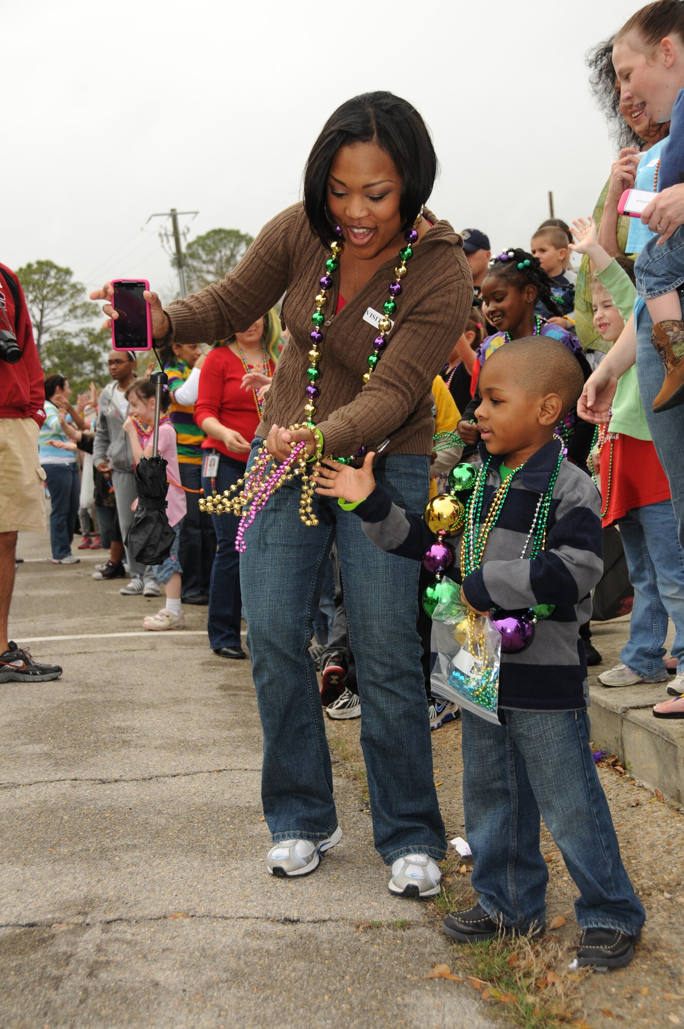 Ayana Hinton and her 4-year-old son Lance catch some beads while they wait for big brother London to pass by during the Jeff Davis Elementary School Mardi Gras parade March 4.  Mrs. Hinton is married to Tech. Sgt. Kendrick Hinton, 81st MDSS.  (U.S. Air Force photo by Kemberly Groue)