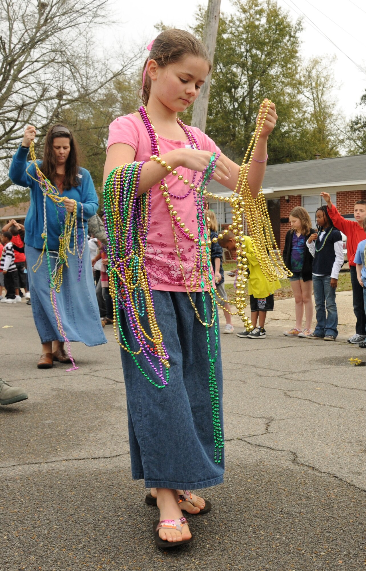 Abigail Cole untangles Mardi Gras beads as she marches in Friday’s Jeff Davis Elementary School Mardi Gras parade in Biloxi. Abigail, 11, is the daughter of Lt.
Col. Richard and Cheryl Cole, 81st Force Support Squadron. Abigail’s parents and her six brothers and sisters also participated in the parade.  (U.S. Air Force photo by Kemberly Groue)