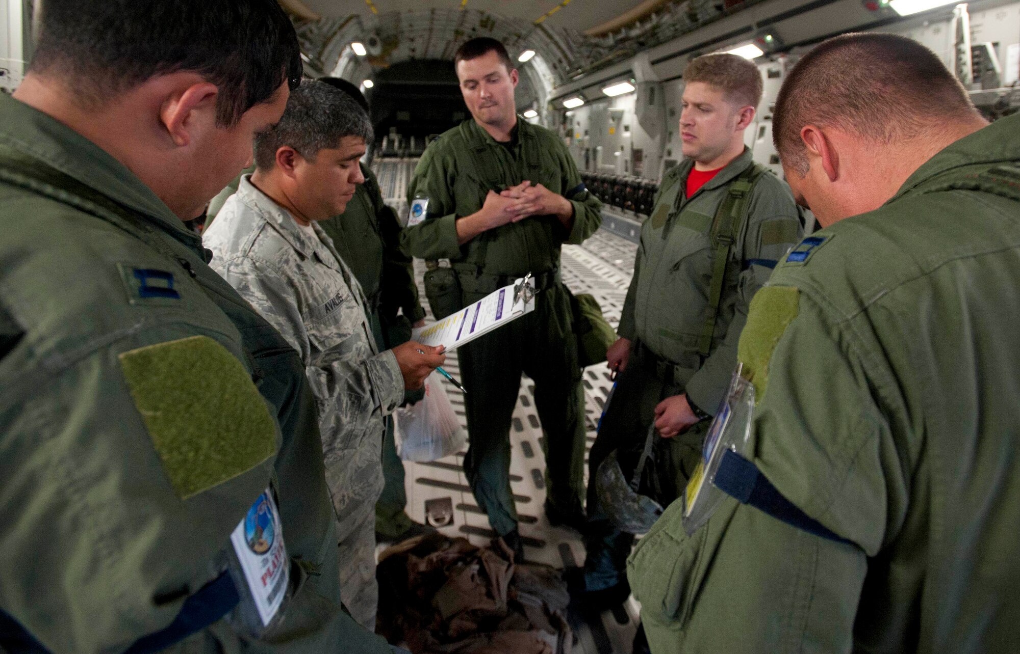 An aircrew that recently landed listens to exercise injects from Staff Sgt. Sergio Avalos, 15th Operations Support Squadron survival, evasion, resistance, and escape specialist (in the Airman Battle Uniform), during an Operational Readiness Exercise Mar. 4 at Joint Base Pearl Harbor Hickam. The ORE tested Airmen's ability to respond to survive and operate during various wartime conditions. (U.S. Air Force photo/Staff Sgt. Nathan Allen)