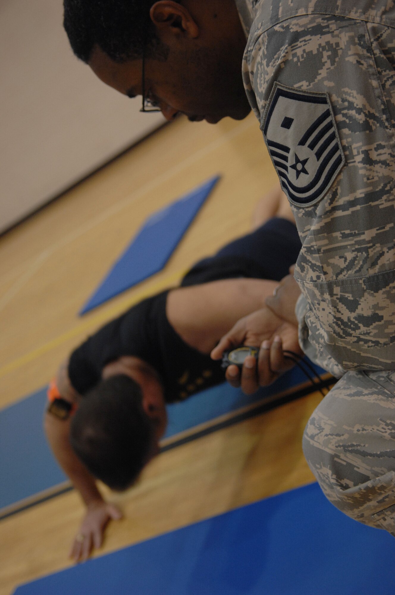 John Musser, Fort Eustis Felker Army Airfield manager, performs push-ups while Master Sgt. Steven Dawson, 633d Force Support Squadron first sergeant, keeps track of the 10 minute time limit during the  Push-up-A-Thon/Sit-up-A-Thon at Langley Air Force Base, Va., March 11, 2011. Langley first sergeants sponsored the event at the Shellbank Fitness Center in support of the Enlisted Heritage Hall museum. (U.S. Air Force photo by Airman 1st Class Racheal Watson/Released)