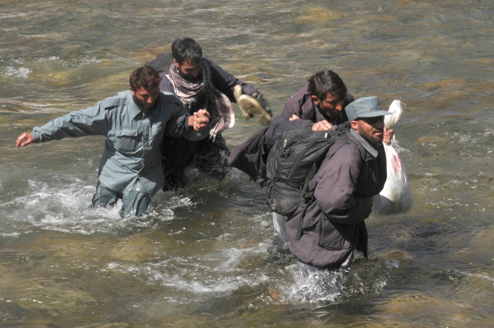 Barge Matal, Afghanistan – Afghan National Police troops wade through knee-high water to reach Mi-17 helicopters that will transport them back to their homes as part of a combat resupply mission in Barge Matal in the northern Kunar Valley March 10. The Afghan Air Force worked in cooperation with the Ministry of the Interior and coalition forces to complete the mission, using ten aircraft to deliver over 9,000 kilograms of weapons, ammunition and food to Afghan National Police stationed in the remote post that is seen as vital by Afghan officials due to its proximity to Pakistan and history of insurgent activity. Following the supply drop-off, forces loaded over 80 ANP bound for their respective homes following a three to six month deployment to the region. (U.S. Navy photo by Mass Communications Specialist 2nd Class Vladimir Potapenko).
