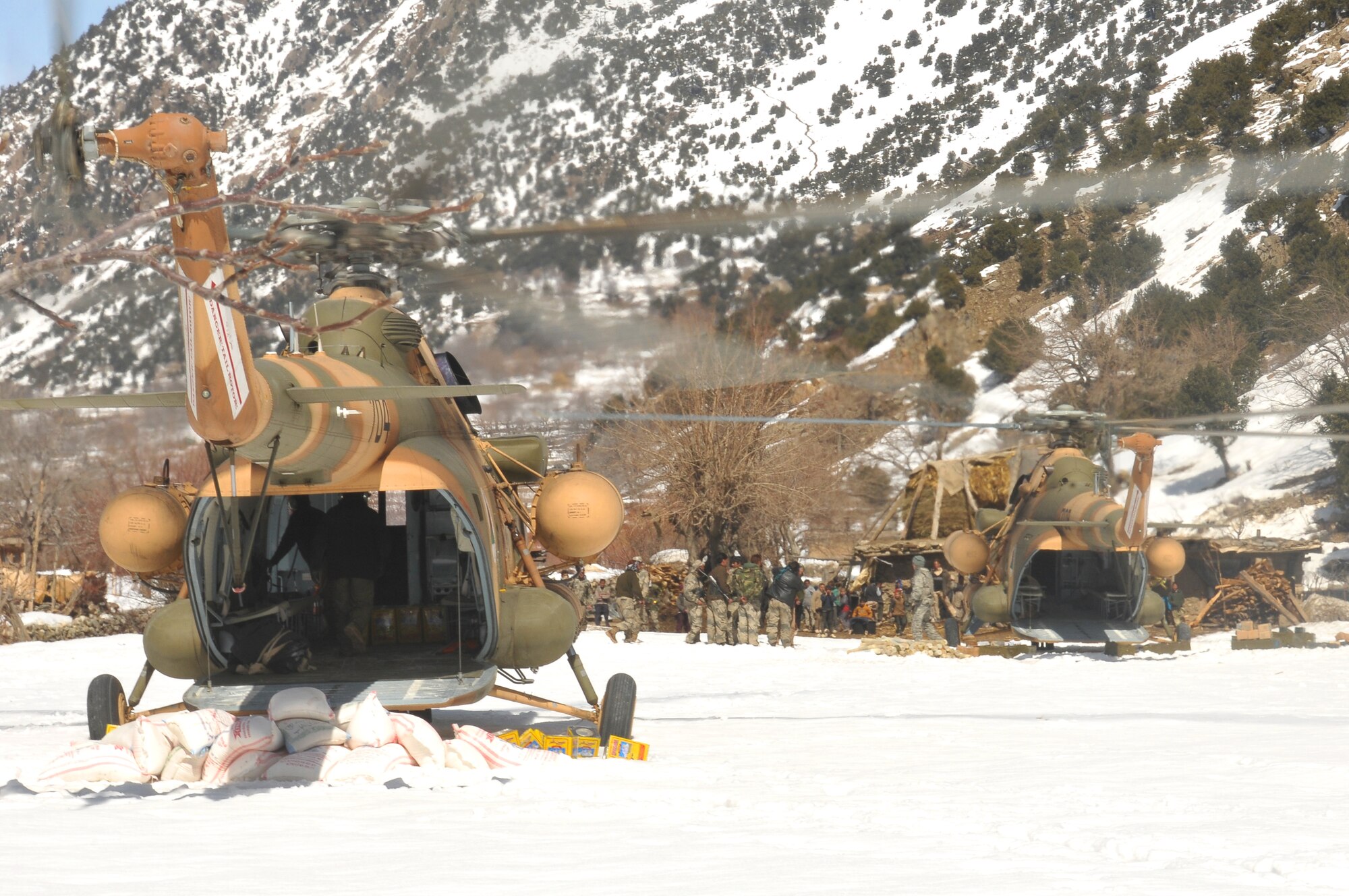 Barge Matal, Afghanistan – Afghan National Police and Afghan Air Force Airmen unload provision from the back of two AAF Mi-17 transport helicopters during a combat resupply mission in Barge Matal in the northern Kunar Valley March 10. The AAF worked in cooperation with the Ministry of the Interior and coalition forces to complete the mission, using ten aircraft to deliver over 9,000 kilograms of weapons, ammunition and food to Afghan National Police stationed in the remote post that is seen as vital by Afghan officials due to its proximity to Pakistan and history of insurgent activity. Following the supply drop-off, forces loaded over 80 ANP bound for their respective homes following a three to six month deployment to the region. (U.S. Navy photo by Mass Communications Specialist 2nd Class Vladimir Potapenko).