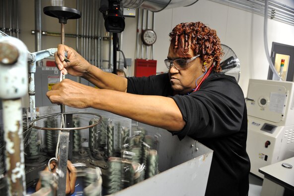 Dorothy Ross, with the 402nd Electronics Maintenance Group’s Manufacturing Flight, prepares to mechanically braid a fireproof covering over a wire harness. U.S. Air Force photo by Tommie Horton


