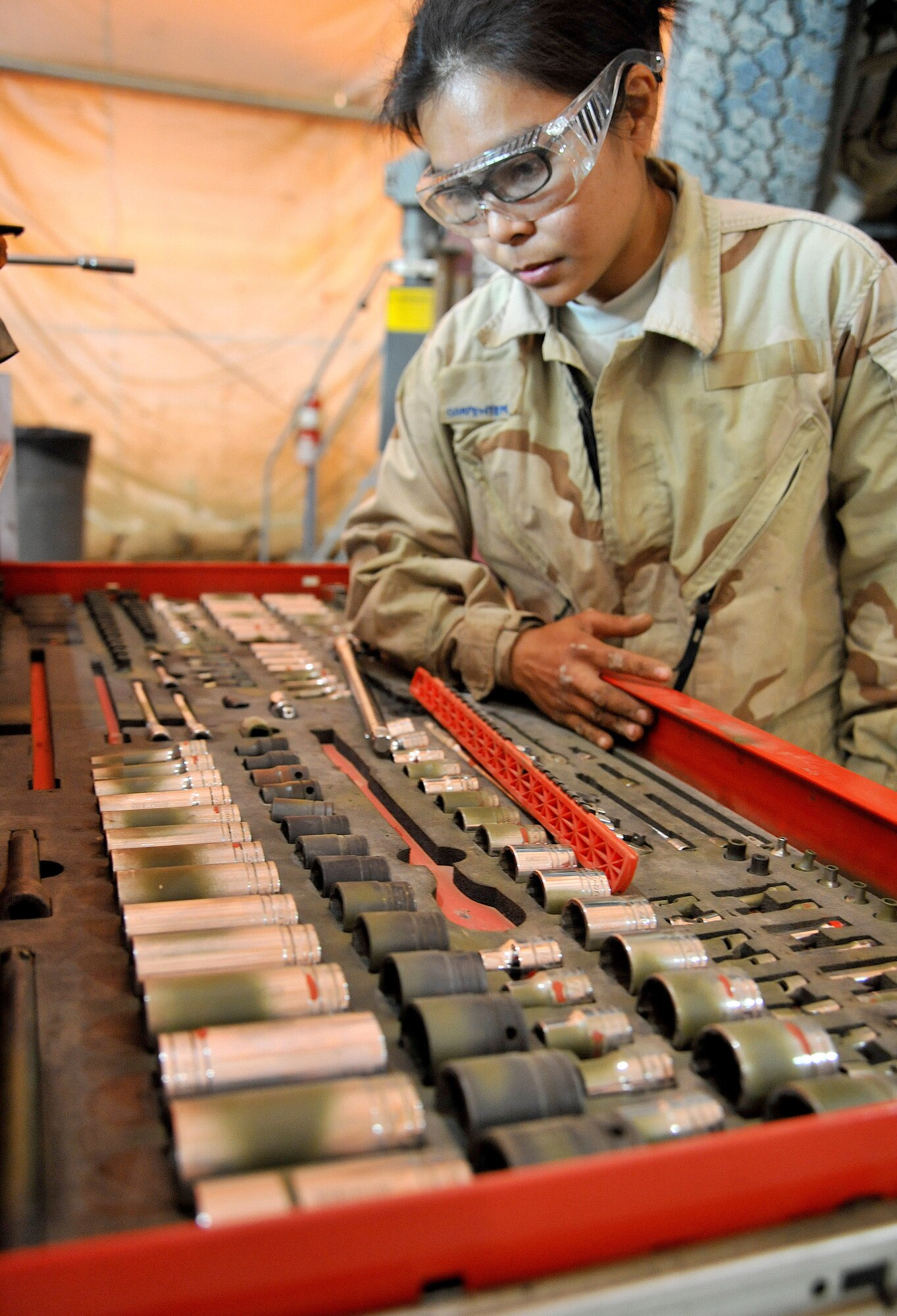 Senior Airman Catherine Carpenter, 407th Expeditionary Operations Support Squadron special purpose vehicle mechanic, looks for the right tool to use March 1, 2011, at Ali Air Base, Iraq. (U.S. Air Force photo by Senior Airman Andrew Lee/Released) 
