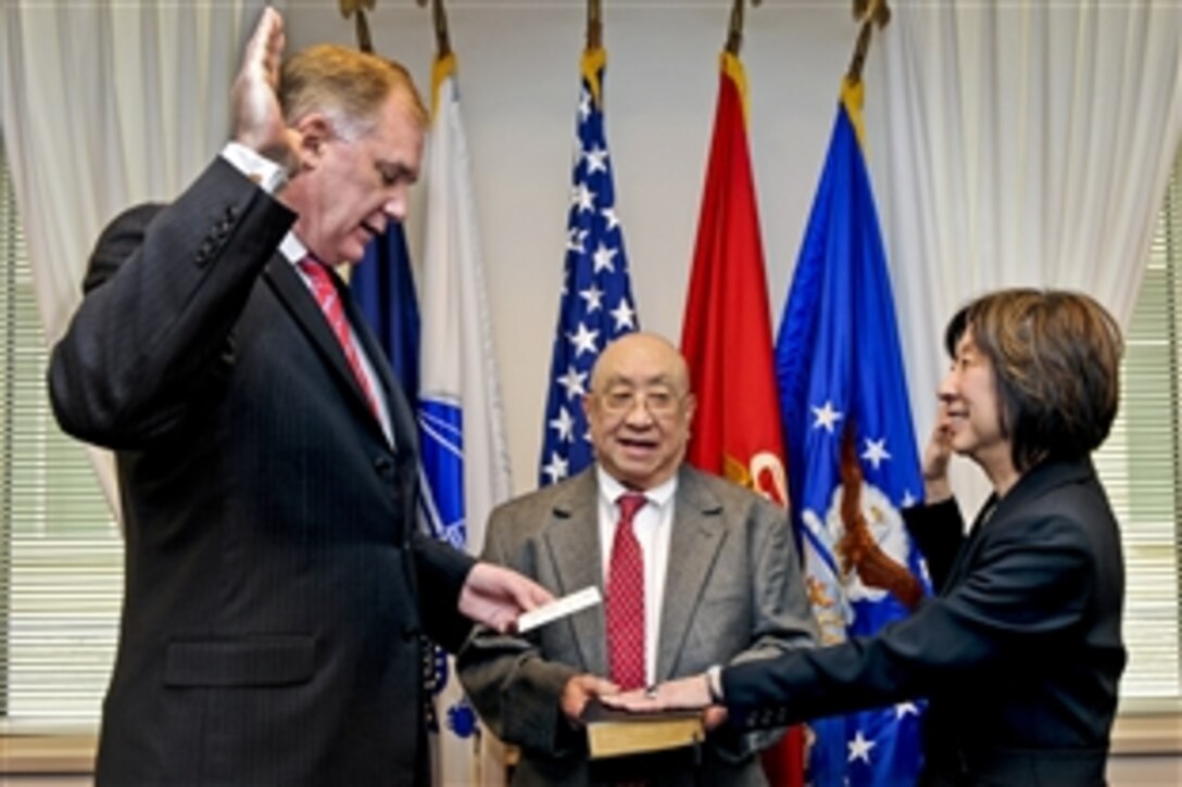 Deputy Defense Secretary William J. Lynn III administers the oath of office to Teresa M. Takai, newly appointed assistant defense secretary for networks and information integration, and the department's chief information officer at the Pentagon, March 11, 2011. Masao Takai, the new official's father, held the Bible for the swearing-in ceremony.