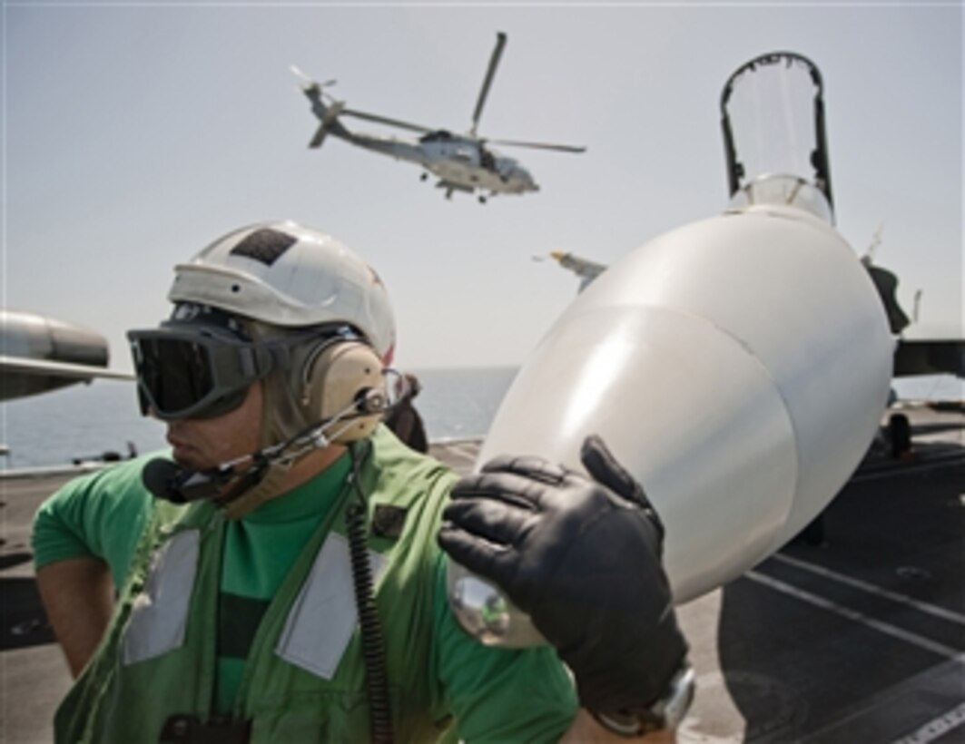 Chief Petty Officer Todd Wing, assigned to Strike Fighter Squadron 25, waits with an F/A-18C Hornet as it is readied for a mission on the flight deck of the aircraft carrier USS Carl Vinson (CVN 70) underway in the Arabian Sea on March 9, 2011.  The Carl Vinson Carrier Strike Group is deployed supporting maritime security operations and theater security cooperation efforts in the U.S. 5th Fleet area of responsibility.  