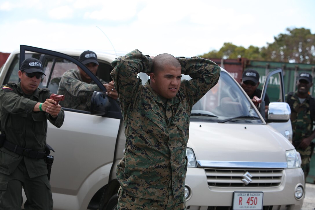Lance Cpl. Raymond Reyes, an administrative specialist with Headquarters and Service Company, 4th Reconnaissance Battalion, role-plays as a mock criminal suspect and is detained by several Caribbean and South American civilian and military law enforcement personnel during a mock vehicle search March 11 as part of exercise Tradewinds 2011.::r::::n::
