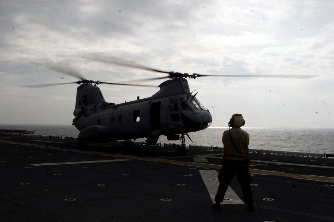 A Sailor with Amphibious Squadron 11 waits to direct a CH-46E Sea Knight helicopter with Marine Medium Helicopter Squadron 262 (reinforced), 31st Marine Expeditionary Unit, during flight deck operations, March 13. Marines and sailors of the 31st MEU aboard the USS Essex (LHD 2) are making preparations for potential humanitarian assistance and disaster relief efforts after an 8.9 earthquake and subsequent tsunami struck Japan causing widespread damage. The USS Essex and 31st MEU are heading for the northeast coast of Japan to be ready to support to our friends and allies in their ongoing efforts and to be near enough to provide that support if called upon.