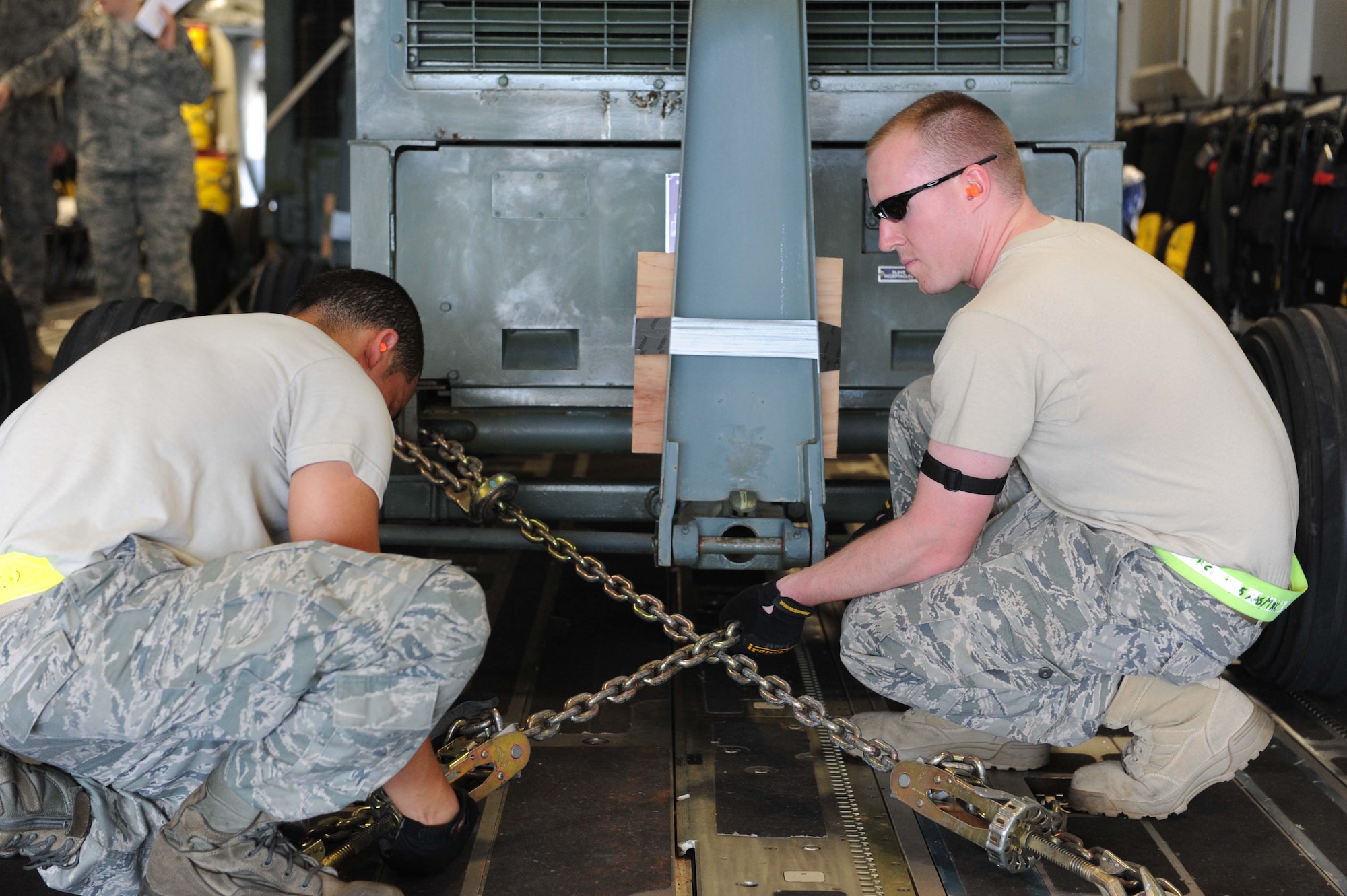 Airman 1st Class James Limon and Senior Airman Kevin Kust, 735th Air Mobility Squadron ramp service specialists, secure a generator to the floor of a C-17 in preparation for its departure on a  humanitarian mission to Japan Mar. 12 at Joint Base Pearl Harbor-Hickam, Hawaii. The plane will visit various Air Force bases in Japan during its mission to to provide support for Japan relief efforts in the wake of tsunami and earthquake damage there. (U.S. Air Force photo by Staff Sgt. Nathan Allen)