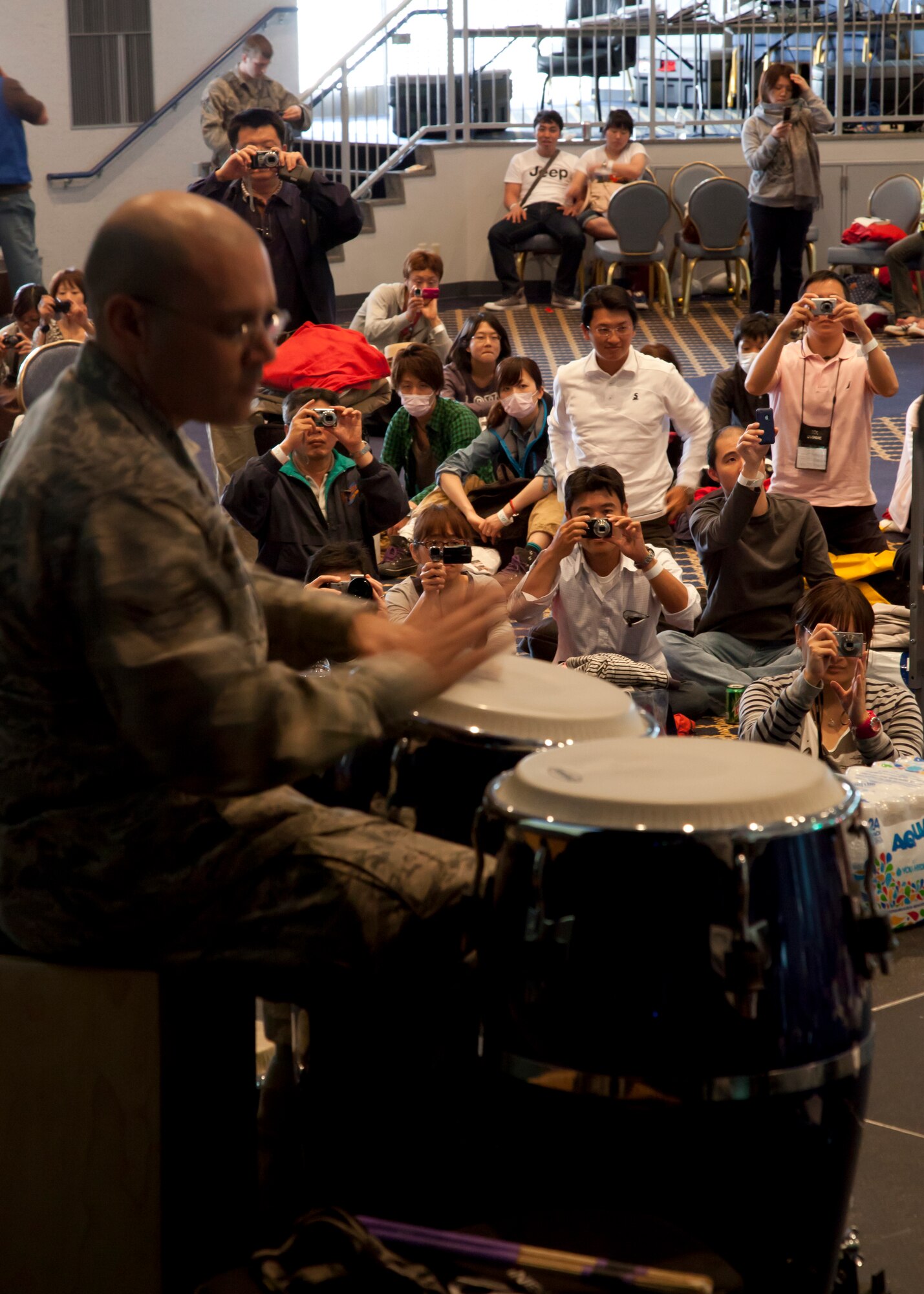 YOKOTA AIR BASE, Japan -- Senior Airman Wilfredo Cruz, U.S. Air Force Band of the Pacific, plays the bongo drums for passengers diverted from Narita International Airport inside the Taiyo Community Center here March 12. The Jazz Combo entertained passengers who stayed overnight as a result of the earthquake in Tokyo. (Courtesy photo)