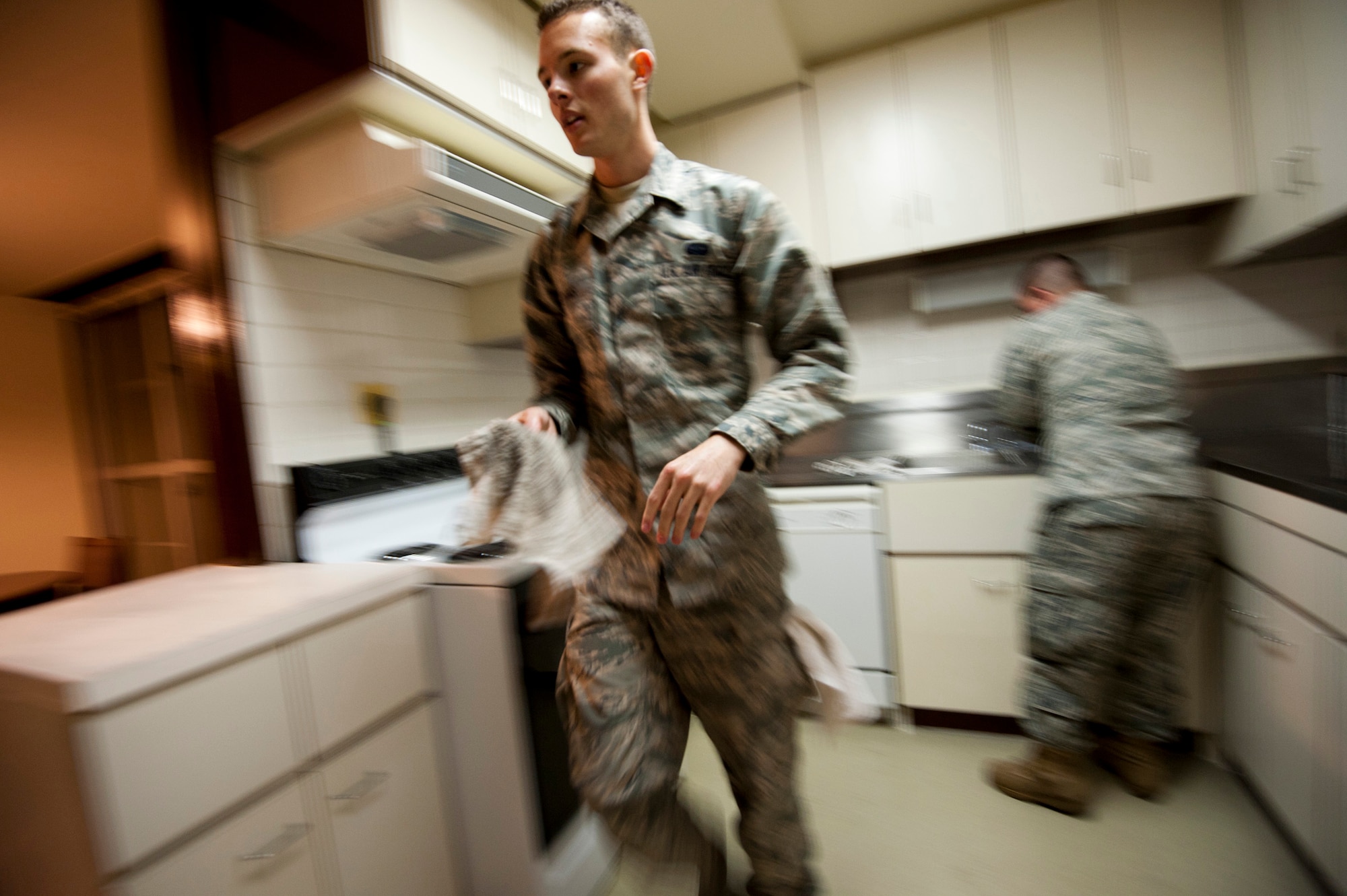 YOKOTA AIR BASE, Japan -- Airman Robert Adams, and Senior Airman Brandon Poturica, 374th Communications Squadron, clean a kitchen here March 12. The two Airmen worked with a team of volunteers and other Airmen to prepare one of the residential towers at Yokota AB for receiving incoming transient aircrew. (U.S. Air Force photo/Staff Sgt. Samuel Morse)