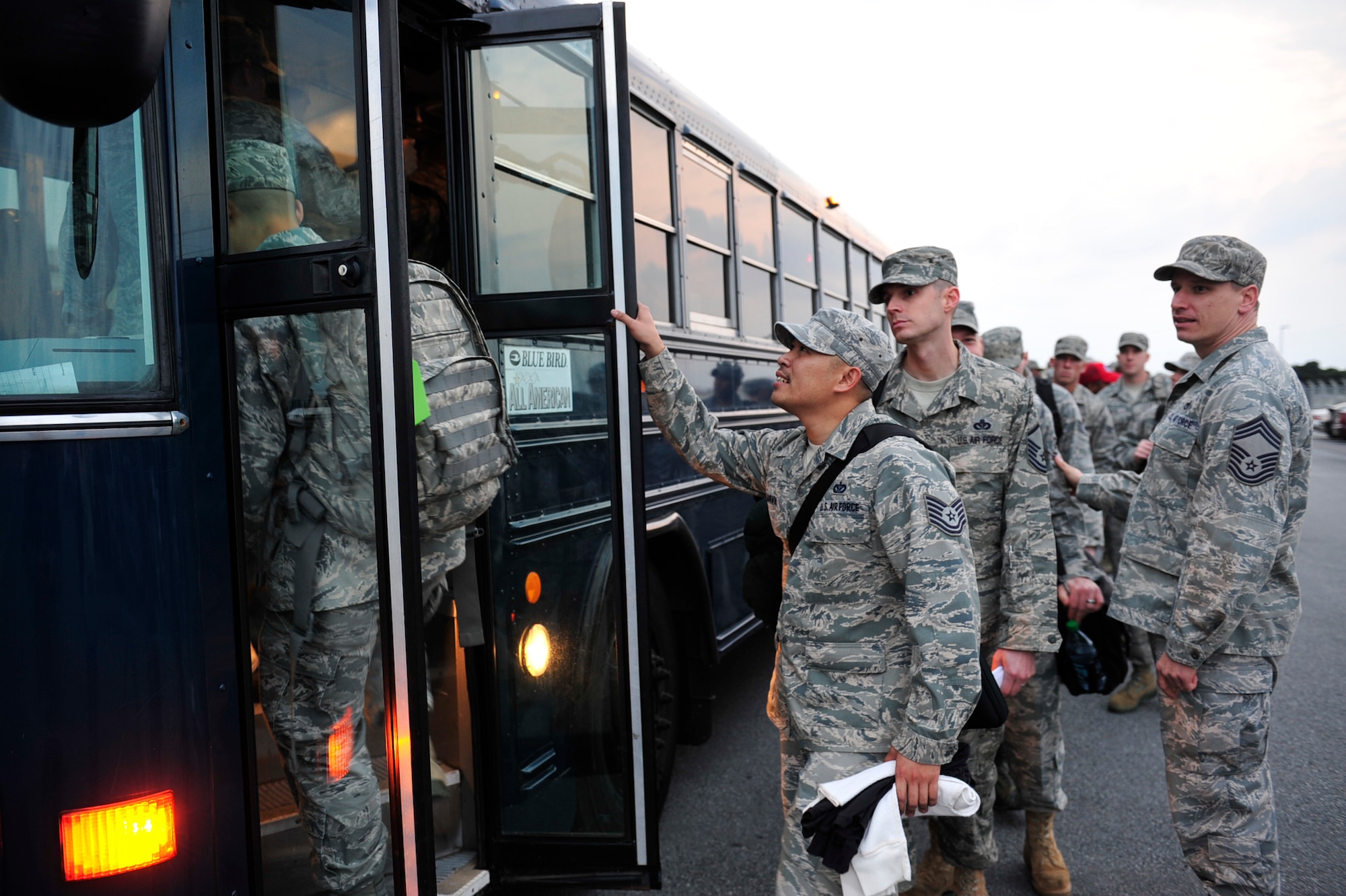 Chief Master Sgt. Robert Rucinski (right) from the 18th Civil Engineer Squadron, looks on as Airmen from his unit board a bus March 12 before departing for Misawa Air Base, in northern Japan. More than 50 members of the 18th CES deployed to Misawa to help restore power and basic services there. (U.S. Air Force photo / Staff Sgt. Lakisha Croley)