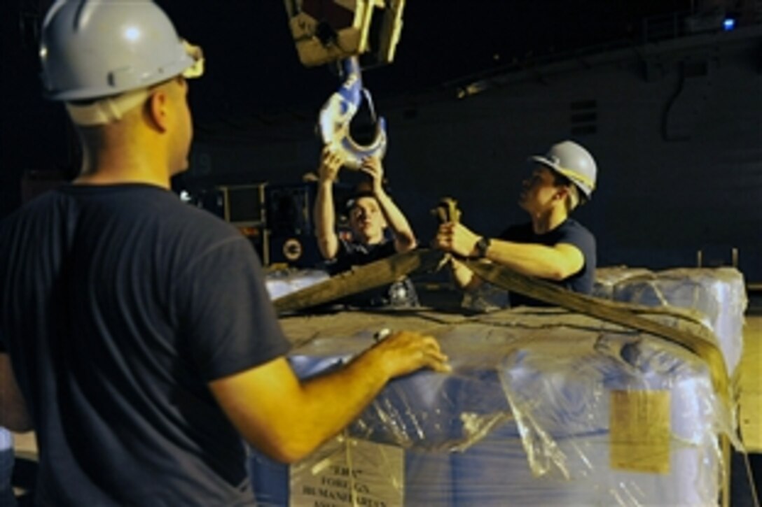 Navy Petty Officer 2nd Class Patrick Ramos, left, Seaman James Norman, center, and Petty Officer 3rd Class Brett Carlson load humanitarian assistance supplies onto the USS Blue Ridge in Singapore, March 11, 2011, to ensure the ship and crew are ready to support earthquake and tsunami relief operations in Japan if directed.  