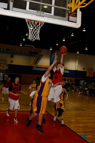 Jun Watanabe, Kokutaiji power forward, jumps over Makkai Legette, Wolverines point guard, during the 2011 Youth Sports Goodwill Basketball Tournament championships at the IronWorks Gym sports courts here March 13. The Wolverines weren’t able to keep Kokutaiji from taking the championship.