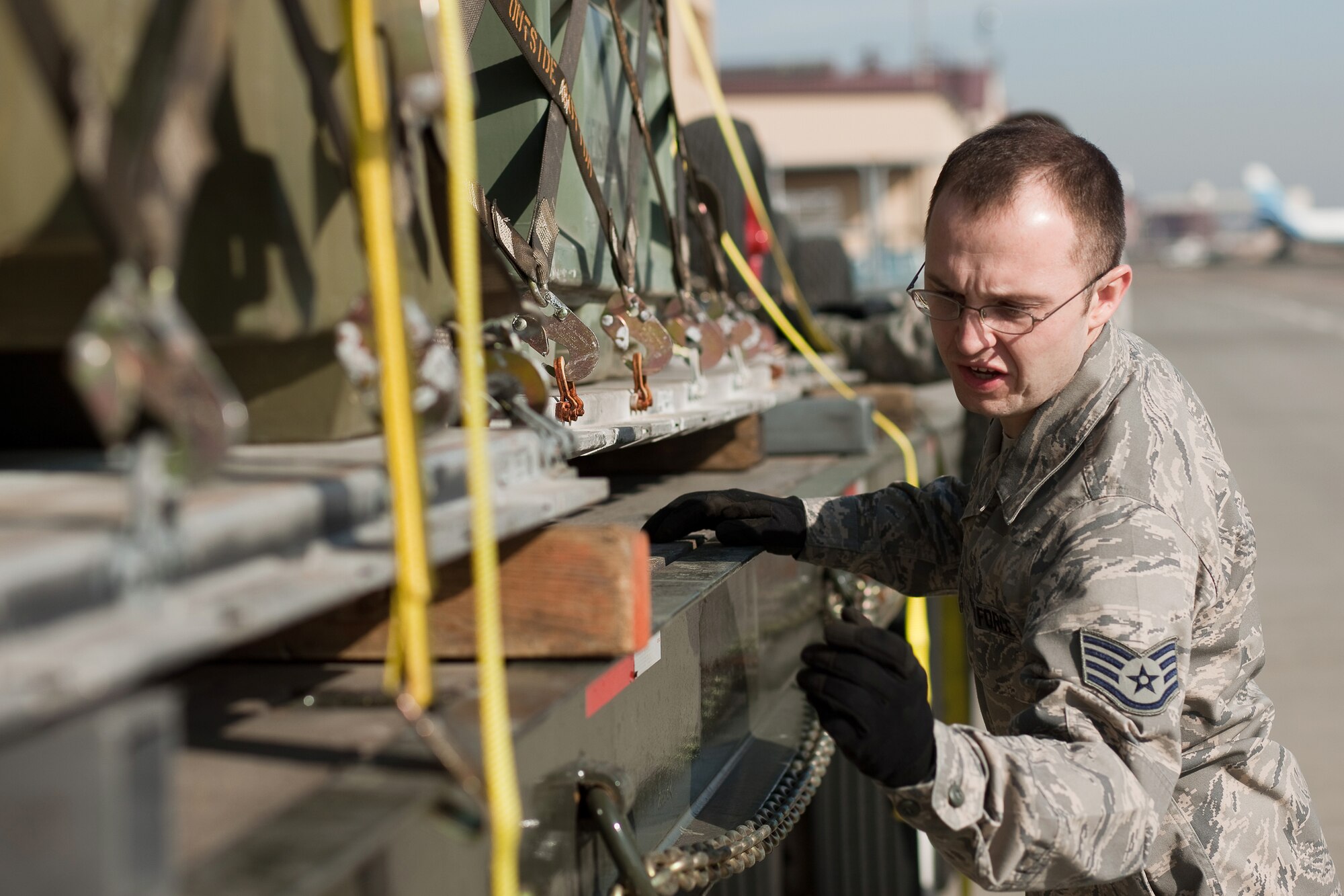 YOKOTA AIR BASE, Japan -- Staff Sgt. Chase Neufeld, 374th Logistics Readiness Squadron, tightens down and inspects a cargo pallet here March 14. The supplies are going to be used to assist the earthquake and tsunami recovery efforts. (U.S. Air Force photo/Osakabe Yasuo)